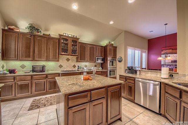 kitchen with hanging light fixtures, a kitchen island, stainless steel appliances, and light tile patterned flooring