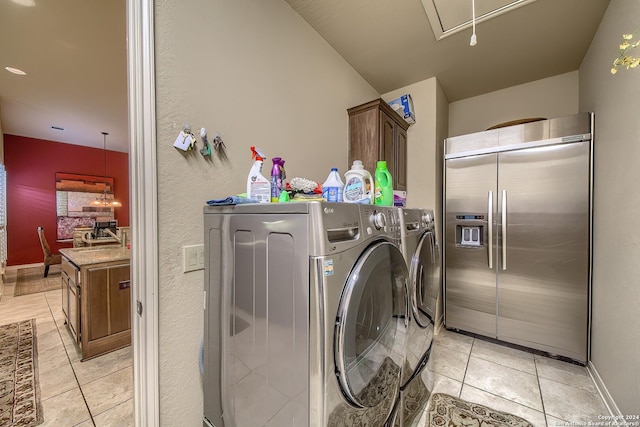 washroom with light tile patterned flooring, washing machine and clothes dryer, and cabinets