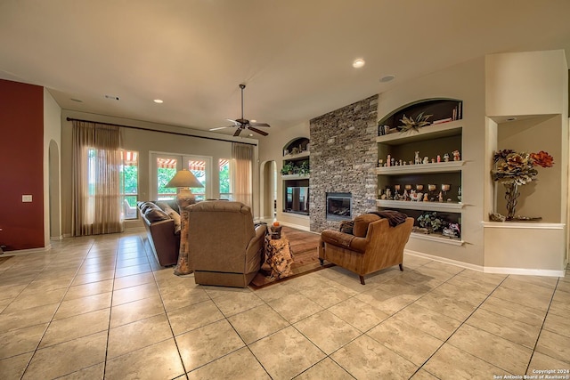 living room featuring light tile patterned flooring, ceiling fan, a fireplace, and built in features