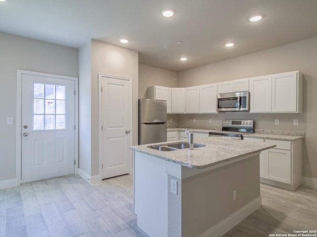 kitchen with stainless steel appliances, white cabinetry, sink, and an island with sink