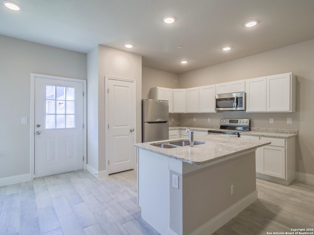 kitchen with stainless steel appliances, sink, a center island with sink, and white cabinets