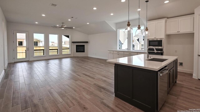 kitchen with wood finished floors, baseboards, light countertops, a sink, and appliances with stainless steel finishes