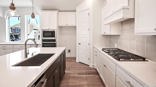 kitchen featuring a sink, light countertops, stainless steel appliances, white cabinetry, and wood finished floors