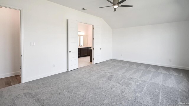 unfurnished bedroom with visible vents, baseboards, lofted ceiling, ensuite bathroom, and carpet