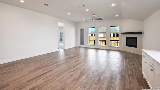 unfurnished living room with a ceiling fan, visible vents, a glass covered fireplace, and light wood-style flooring