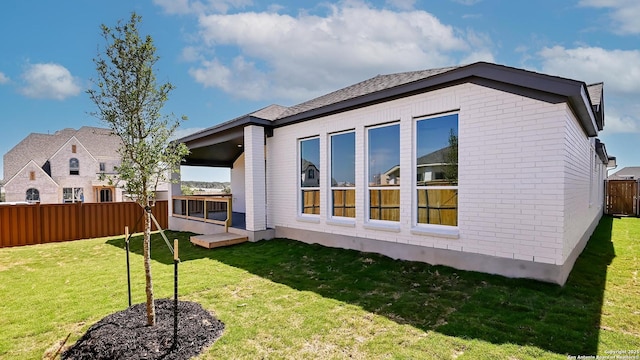 rear view of property featuring a yard, brick siding, and a fenced backyard
