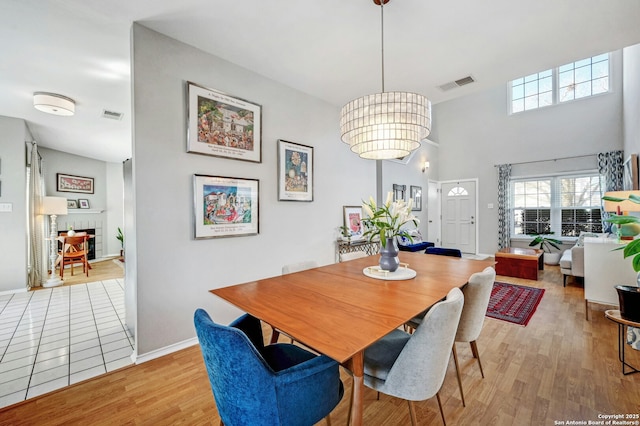 dining room featuring light wood-type flooring, baseboards, a fireplace, and visible vents