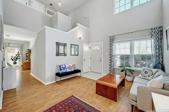 living room featuring visible vents, light wood-style flooring, and baseboards