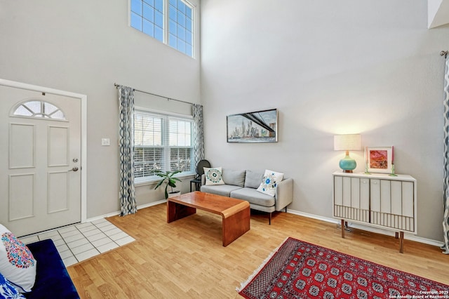 living area with a towering ceiling, baseboards, and wood finished floors