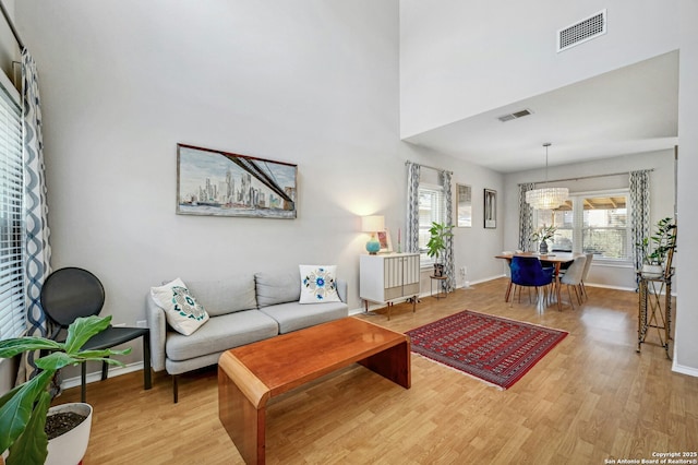 living area featuring light wood-style flooring, visible vents, and baseboards