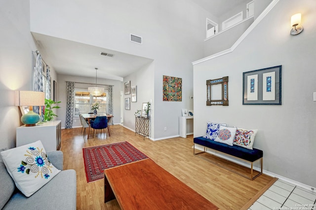 living room with baseboards, a high ceiling, visible vents, and wood finished floors