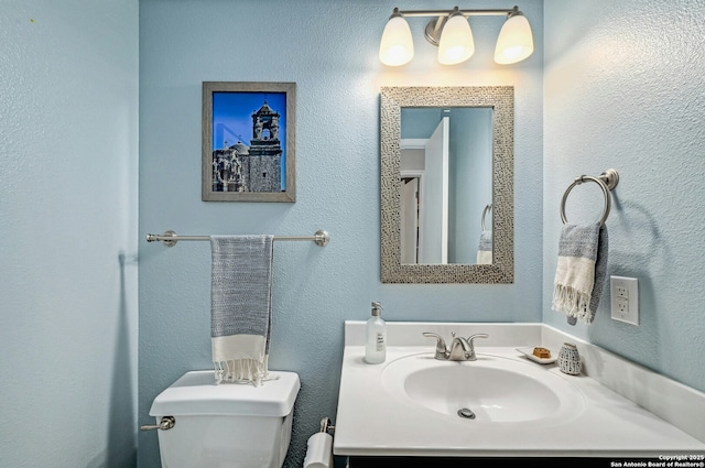 bathroom featuring toilet, a sink, and a textured wall