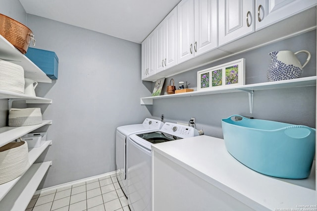 clothes washing area featuring light tile patterned floors, baseboards, washer and clothes dryer, and cabinet space