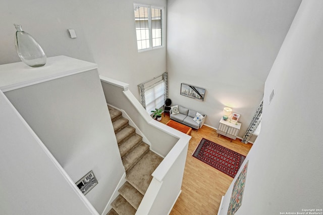 stairway with a towering ceiling, baseboards, and wood finished floors