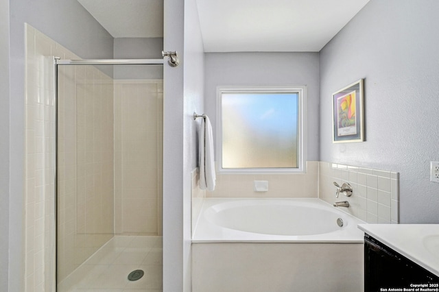 full bathroom featuring a stall shower, a bath, and vanity