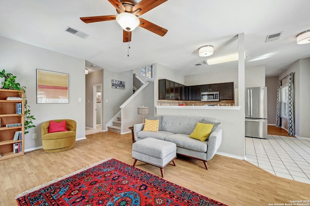 living area with light wood-style floors, stairs, and visible vents