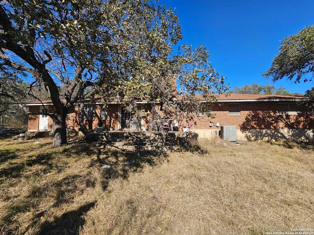 rear view of house with a yard and cooling unit