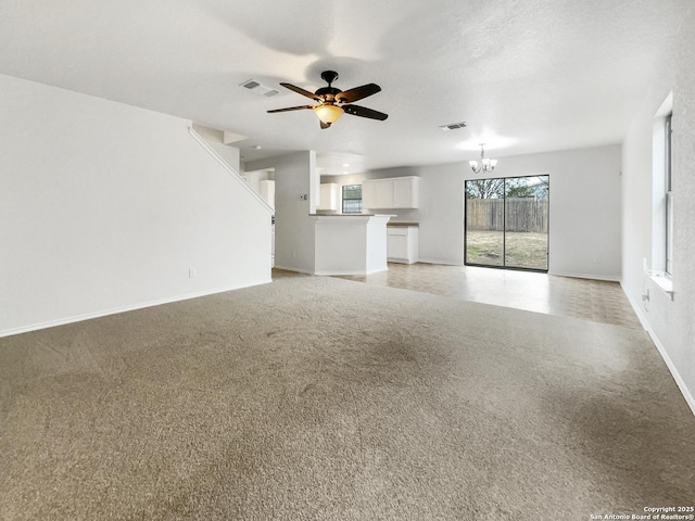 unfurnished living room with ceiling fan with notable chandelier