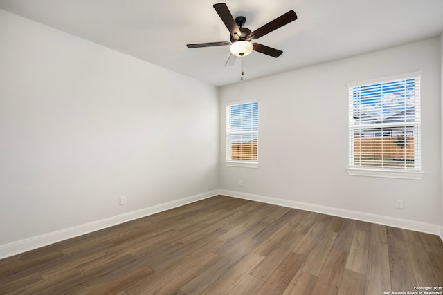 empty room featuring ceiling fan, a healthy amount of sunlight, and dark hardwood / wood-style flooring