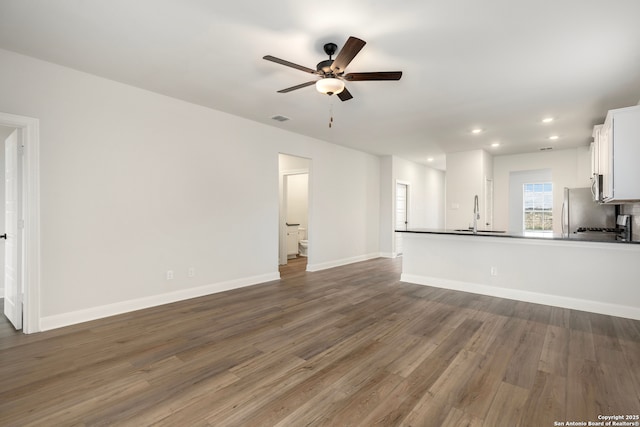 unfurnished living room with ceiling fan, dark hardwood / wood-style flooring, and sink