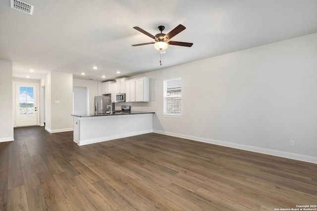 kitchen featuring dark wood-type flooring, white cabinetry, appliances with stainless steel finishes, kitchen peninsula, and ceiling fan