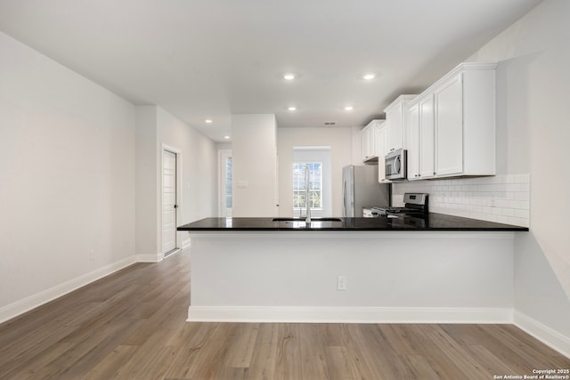 kitchen featuring white cabinetry, appliances with stainless steel finishes, kitchen peninsula, and sink