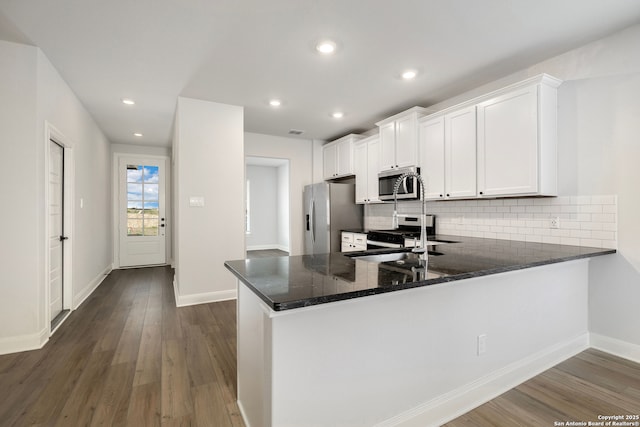 kitchen with sink, appliances with stainless steel finishes, white cabinets, dark hardwood / wood-style flooring, and kitchen peninsula