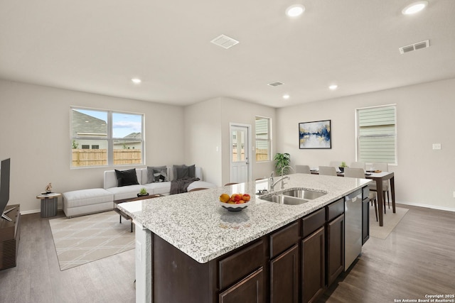 kitchen featuring sink, a kitchen island with sink, stainless steel dishwasher, dark brown cabinetry, and light hardwood / wood-style floors