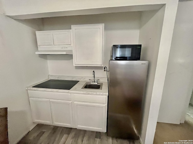 kitchen with white cabinetry, sink, light hardwood / wood-style floors, and black appliances