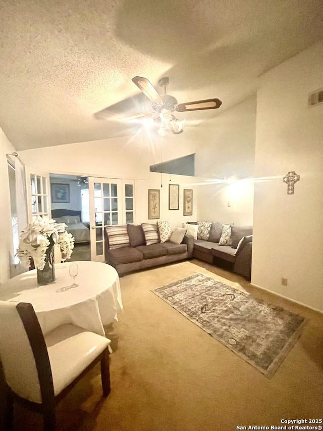 living room with lofted ceiling, carpet floors, ceiling fan, a textured ceiling, and french doors