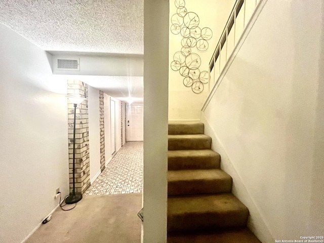 staircase with carpet floors and a textured ceiling