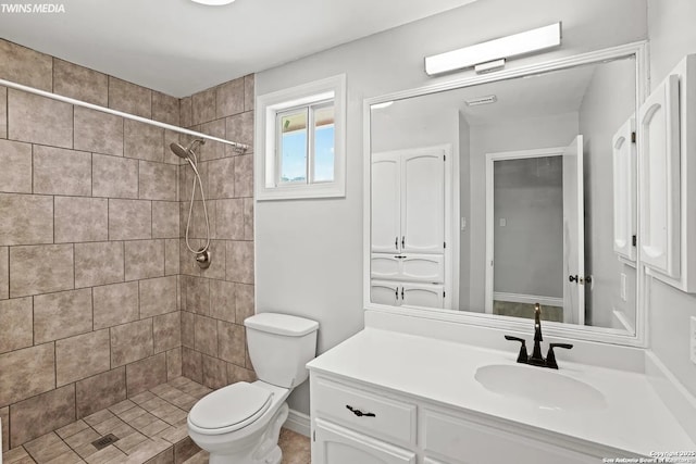 bathroom featuring vanity, a tile shower, and toilet