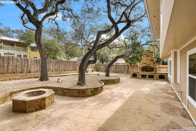 view of patio with a fire pit and an outdoor stone fireplace