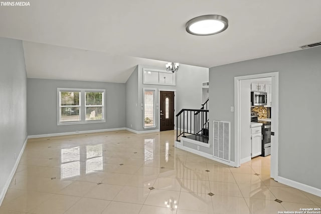 tiled entryway featuring a chandelier and vaulted ceiling