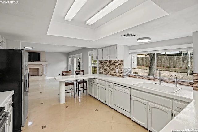 kitchen with sink, dishwasher, white cabinetry, stainless steel fridge with ice dispenser, and decorative backsplash