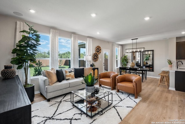 living room featuring a healthy amount of sunlight, a chandelier, and light hardwood / wood-style flooring