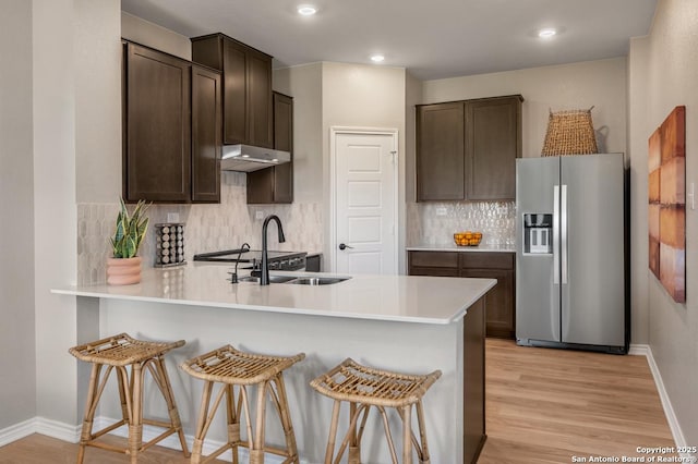 kitchen with sink, a kitchen breakfast bar, kitchen peninsula, and stainless steel refrigerator with ice dispenser