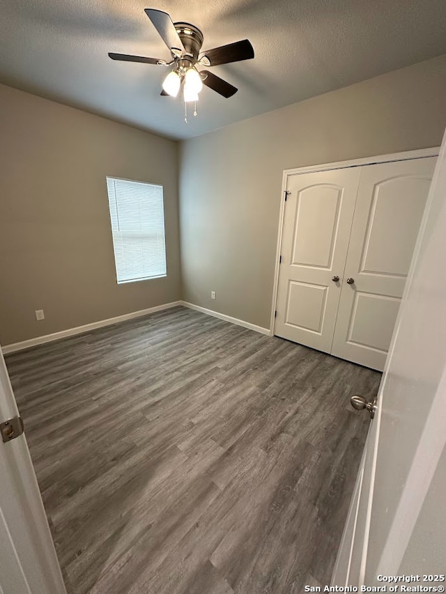 empty room featuring ceiling fan, a textured ceiling, and dark hardwood / wood-style flooring