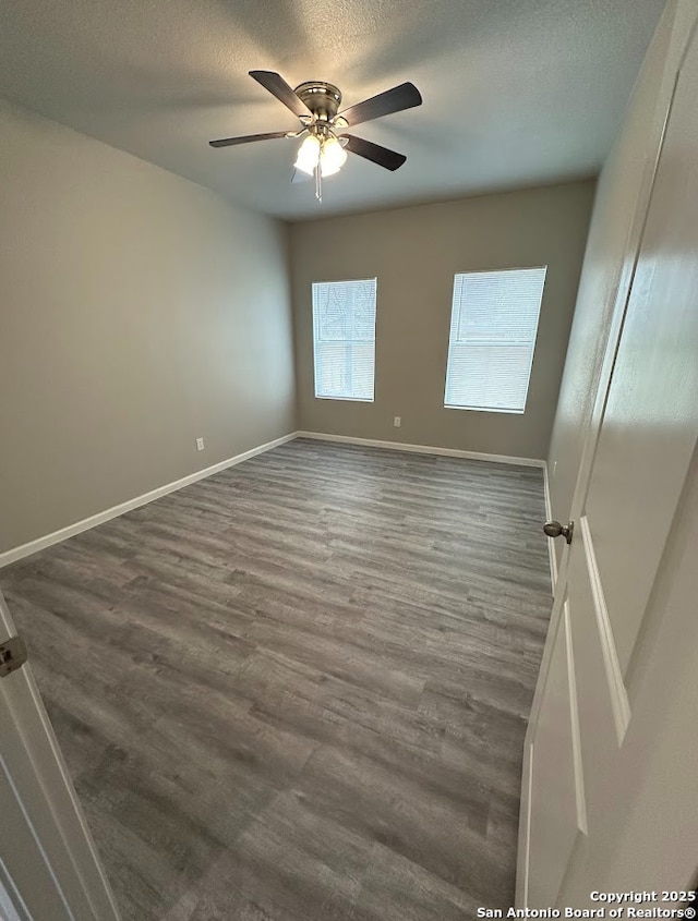 unfurnished room featuring dark wood-type flooring, ceiling fan, and a textured ceiling