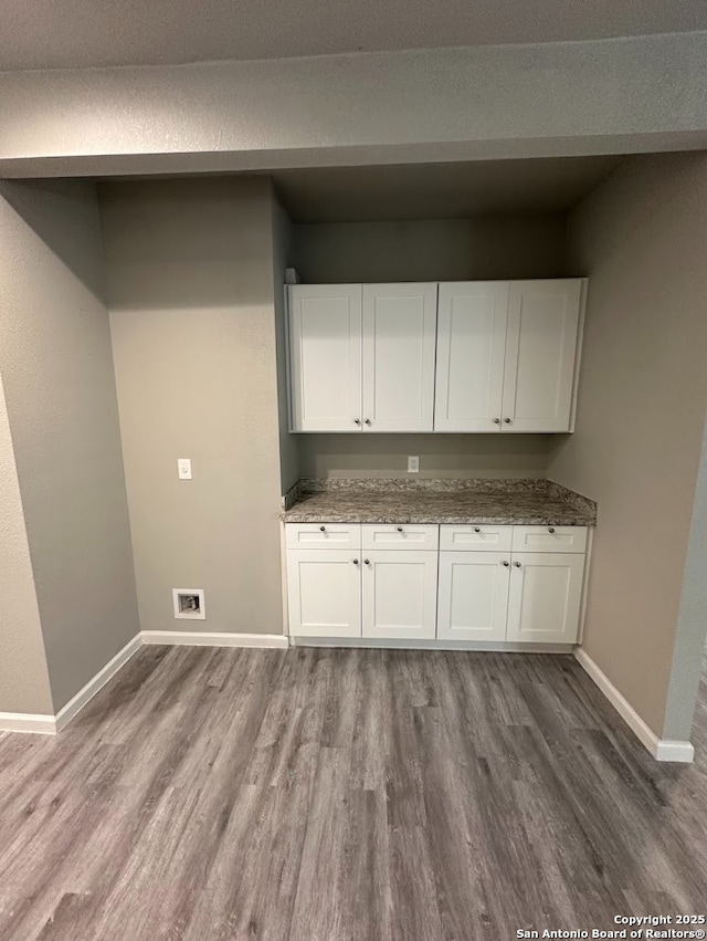 clothes washing area with cabinets, hardwood / wood-style flooring, and washer hookup