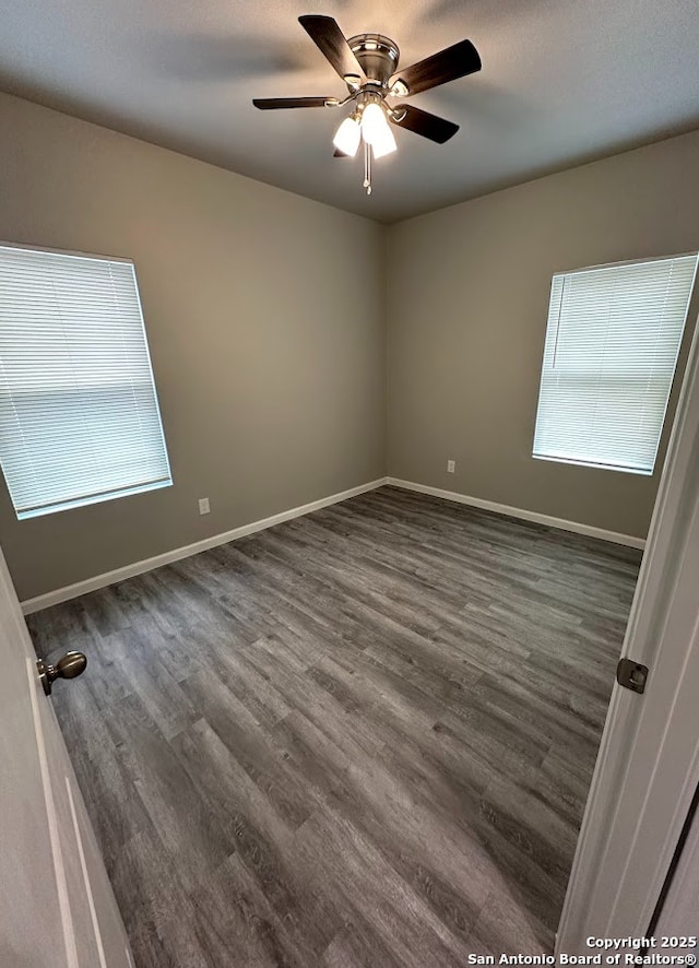 unfurnished room with plenty of natural light, dark wood-type flooring, and ceiling fan