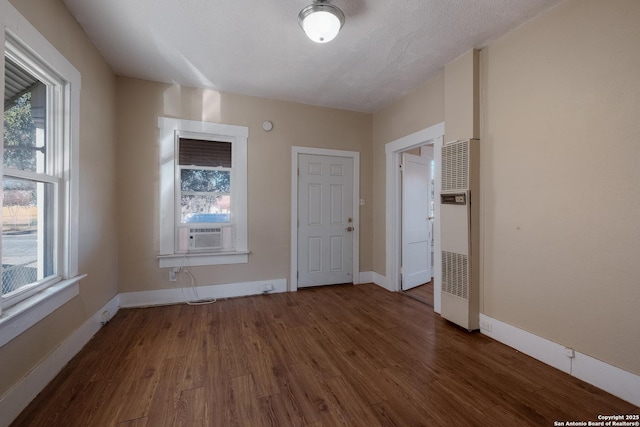 unfurnished room featuring cooling unit, dark wood-type flooring, and plenty of natural light