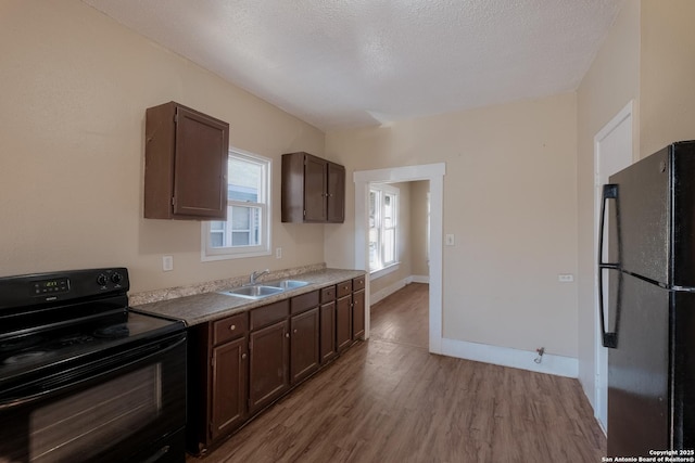 kitchen featuring sink, dark brown cabinetry, black appliances, light hardwood / wood-style floors, and a textured ceiling