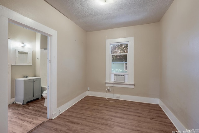 spare room featuring cooling unit, wood-type flooring, and a textured ceiling