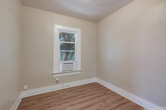 unfurnished room with hardwood / wood-style floors, a textured ceiling, and cooling unit