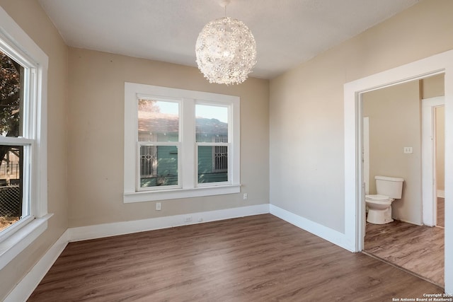 unfurnished dining area with wood-type flooring and a chandelier