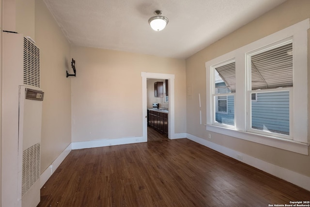 spare room featuring dark hardwood / wood-style floors and a textured ceiling