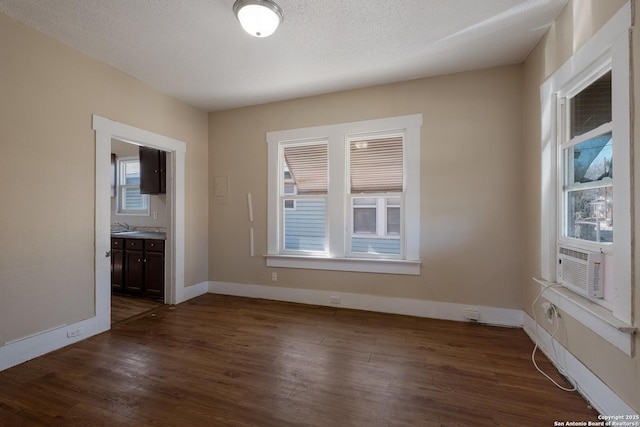 unfurnished room featuring dark hardwood / wood-style flooring, sink, cooling unit, and a textured ceiling