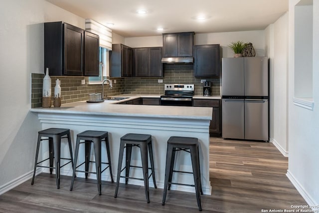 kitchen with appliances with stainless steel finishes, sink, a breakfast bar area, and kitchen peninsula