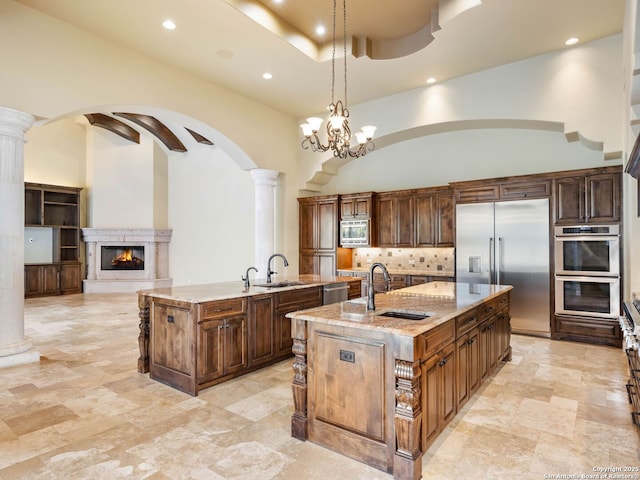 kitchen with built in appliances, a center island with sink, and a high ceiling